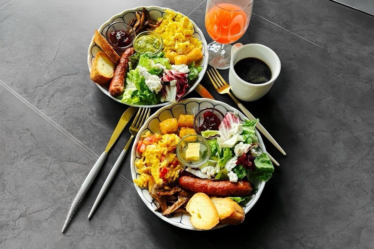 Dos platos de comida con un vaso de jugo de naranja y una taza de café sobre una mesa.