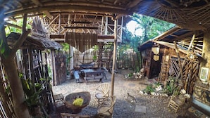 A rustic outdoor seating area with bamboo furniture, a stone table, and a thatched roof structure. - Bamboo Nest Palawan - Hostel (Puerto Princesa)