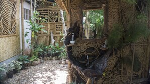 A traditional bamboo structure with intricate lattice work, surrounded by potted plants and a small water feature. - Bamboo Nest Palawan - Hostel (Puerto Princesa)