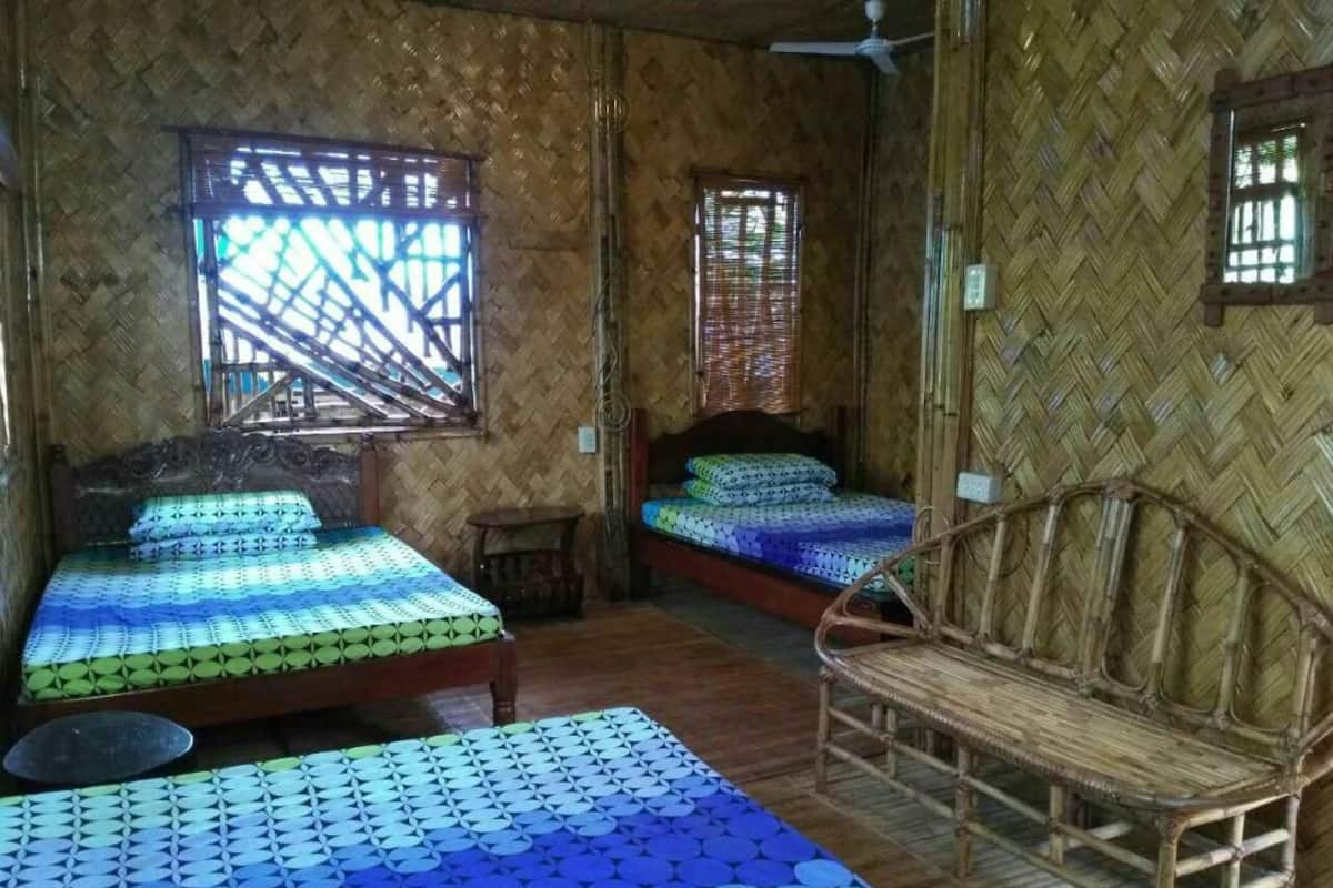 Ein Zimmer mit zwei Betten, einem Korbsessel und einem Deckenventilator.