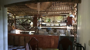 A kitchen with a bar area, a tiled floor, and a dining table with chairs. - Bamboo Nest Palawan - Hostel (Puerto Princesa)