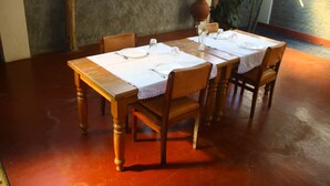 Una mesa de comedor dispuesta con manteles blancos, platos y cubiertos.