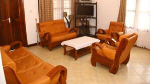 Una sala de estar con un sofá, una mesa de centro y un televisor sobre un mueble.