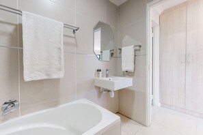A modern bathroom with a bathtub, a sink, and a mirror. - Tokai Royale (Cape Town)