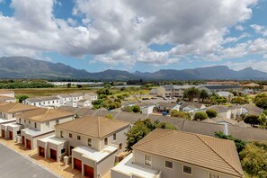 A residential area with modern houses, a parking lot, and mountains in the background. - Tokai Royale (Cape Town)