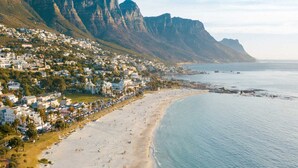 Uma cidade costeira com praia, casas e montanhas ao fundo.