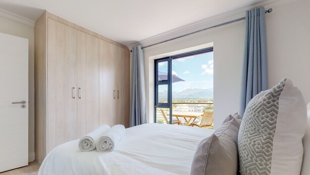 Quarto de hotel com uma cama, um guarda-roupa e vista para o exterior.