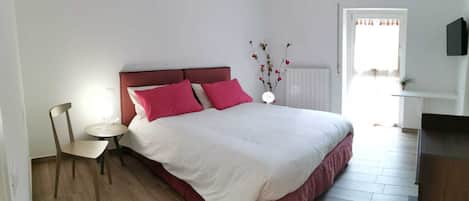 Een slaapkamer met een bed, een stoel, een klein tafeltje en een radiator.