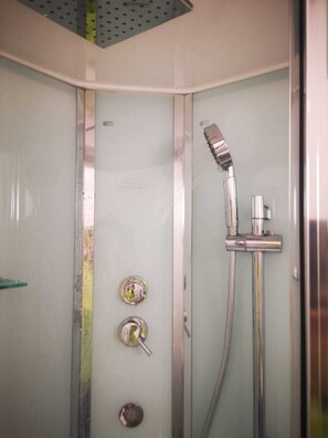 A shower with a handheld showerhead and a wall-mounted faucet.