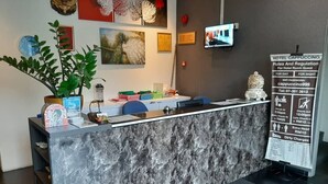 A hotel reception desk with a marble counter, a potted plant, and a sign detailing hotel rules and regulations.