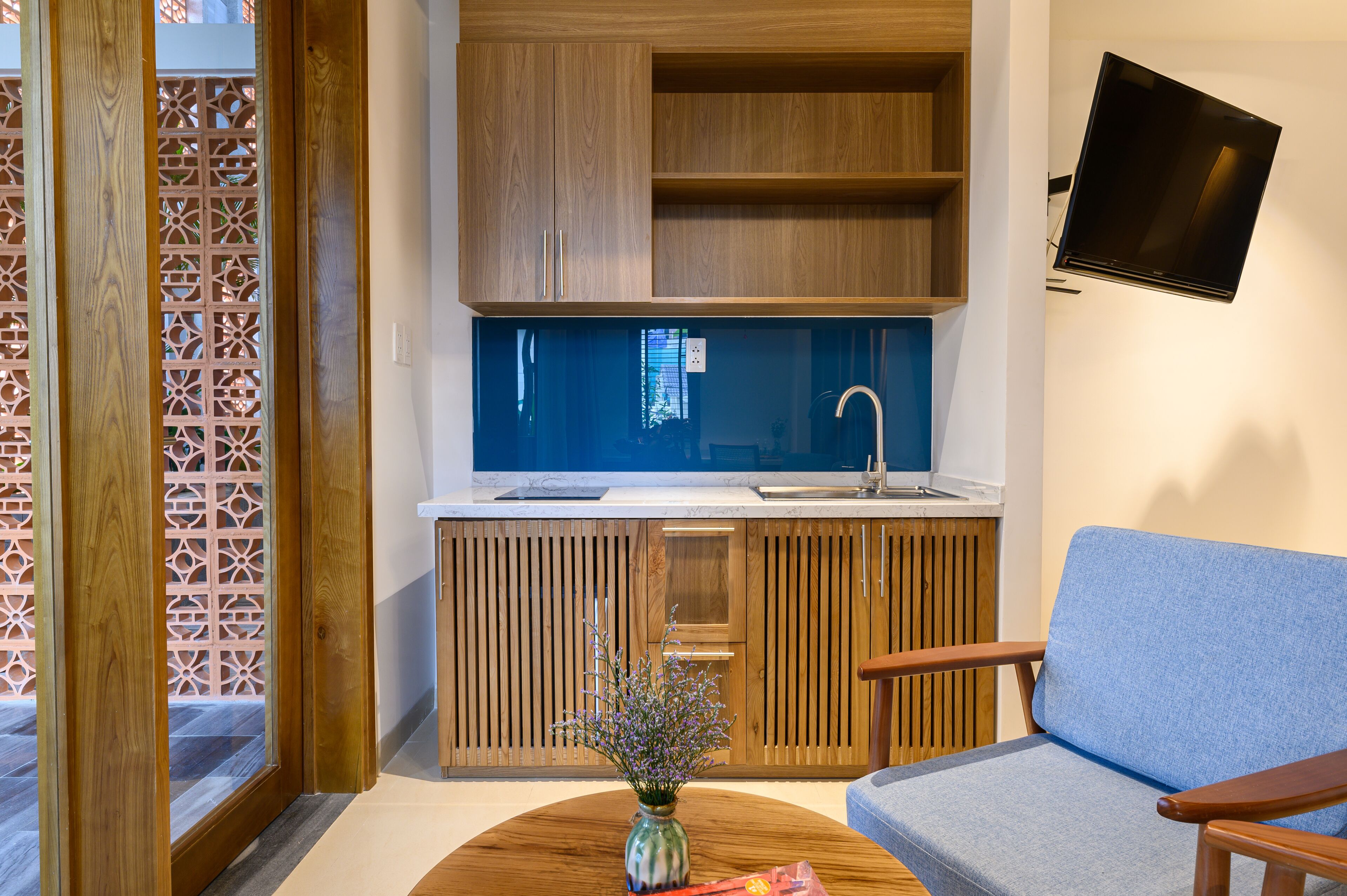 A modern kitchen with wooden cabinets, a built-in sink, and a flat-screen TV mounted on the wall.
