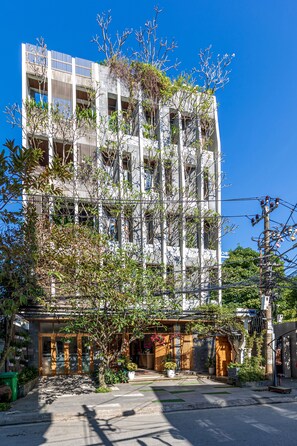 Ein mehrstöckiges Gebäude mit moderner Architektur, mit Balkonen und einer Mischung aus offenen und geschlossenen Bereichen.