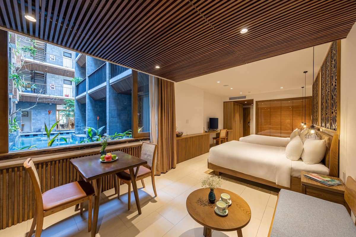 Habitación de hotel moderna con una cama grande, una mesa de comedor y vistas a un patio.