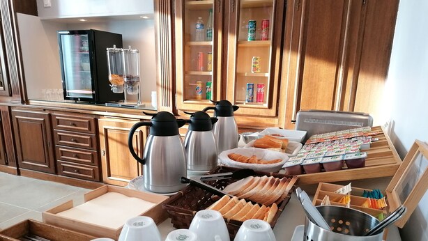 A breakfast buffet setup with coffee makers, pastries, and a variety of beverages.