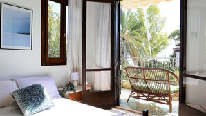 Une chambre avec un lit, une chaise, une fenêtre et une vue sur la verdure.