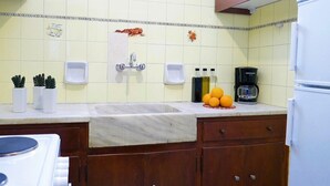 Une cuisine équipée d’un plan de travail en marbre, d’un évier, d’une machine à café et d’un réfrigérateur.
