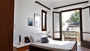 Une chambre à coucher avec un lit, une table de chevet, une lampe et une vue sur l’extérieur.