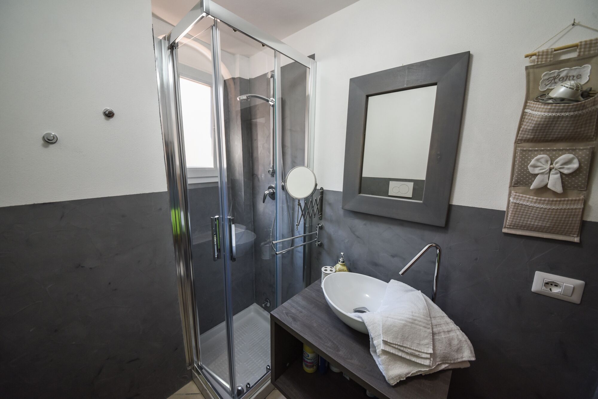 A modern bathroom with a glass-enclosed shower, a dark countertop sink, and a mirror above it.