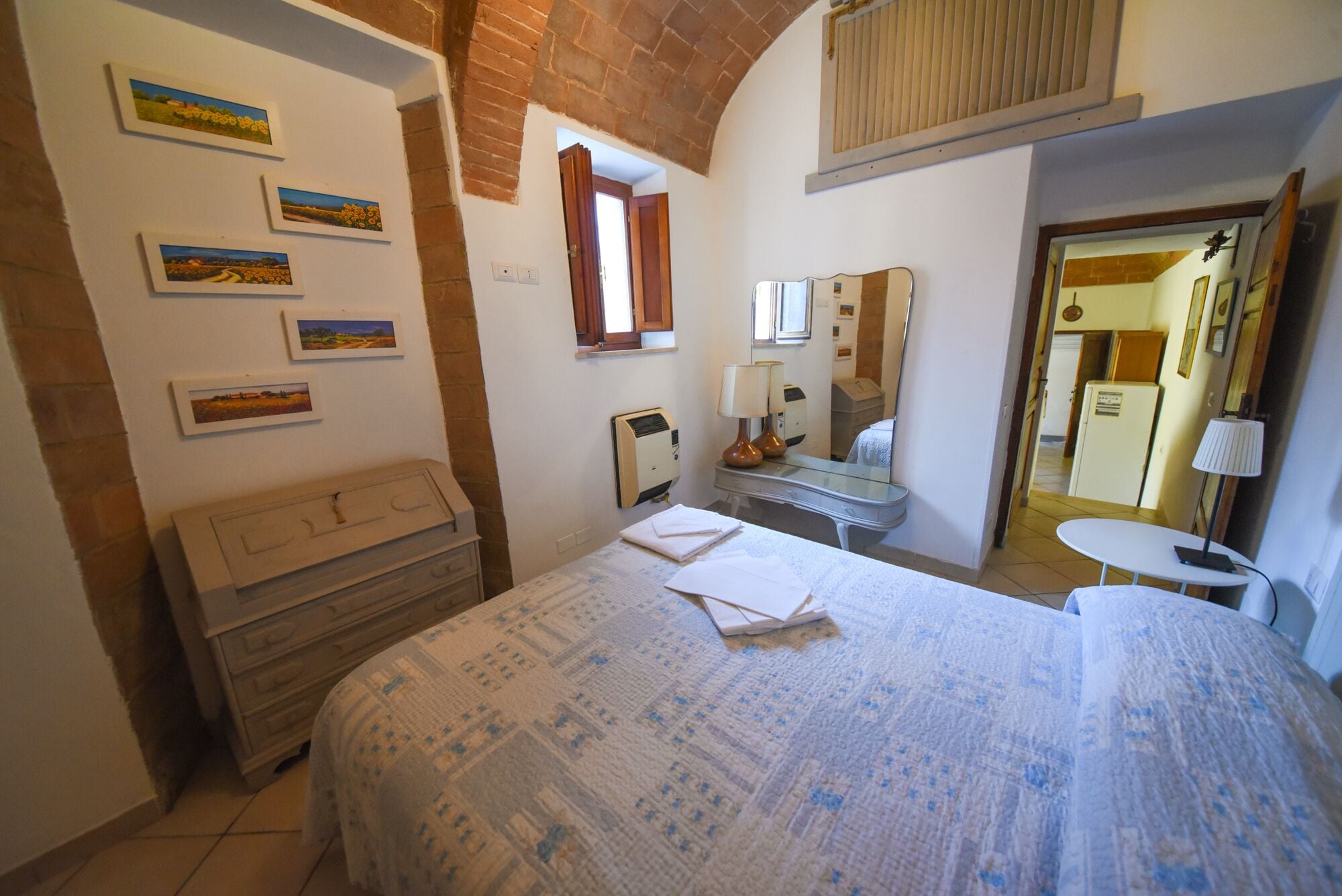 Une chambre à coucher avec un lit, une commode, un miroir et des œuvres d’art accrochées au mur.