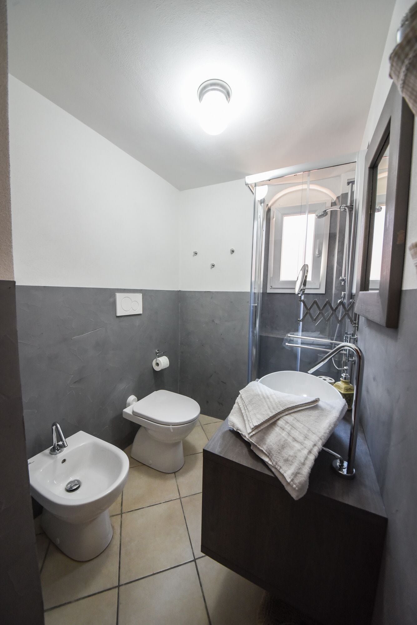 A bathroom with a bidet, toilet, and a shower enclosure.