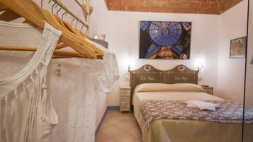Una camera da letto con un letto, un appendiabiti in legno, un comodino e un quadro appeso al muro.