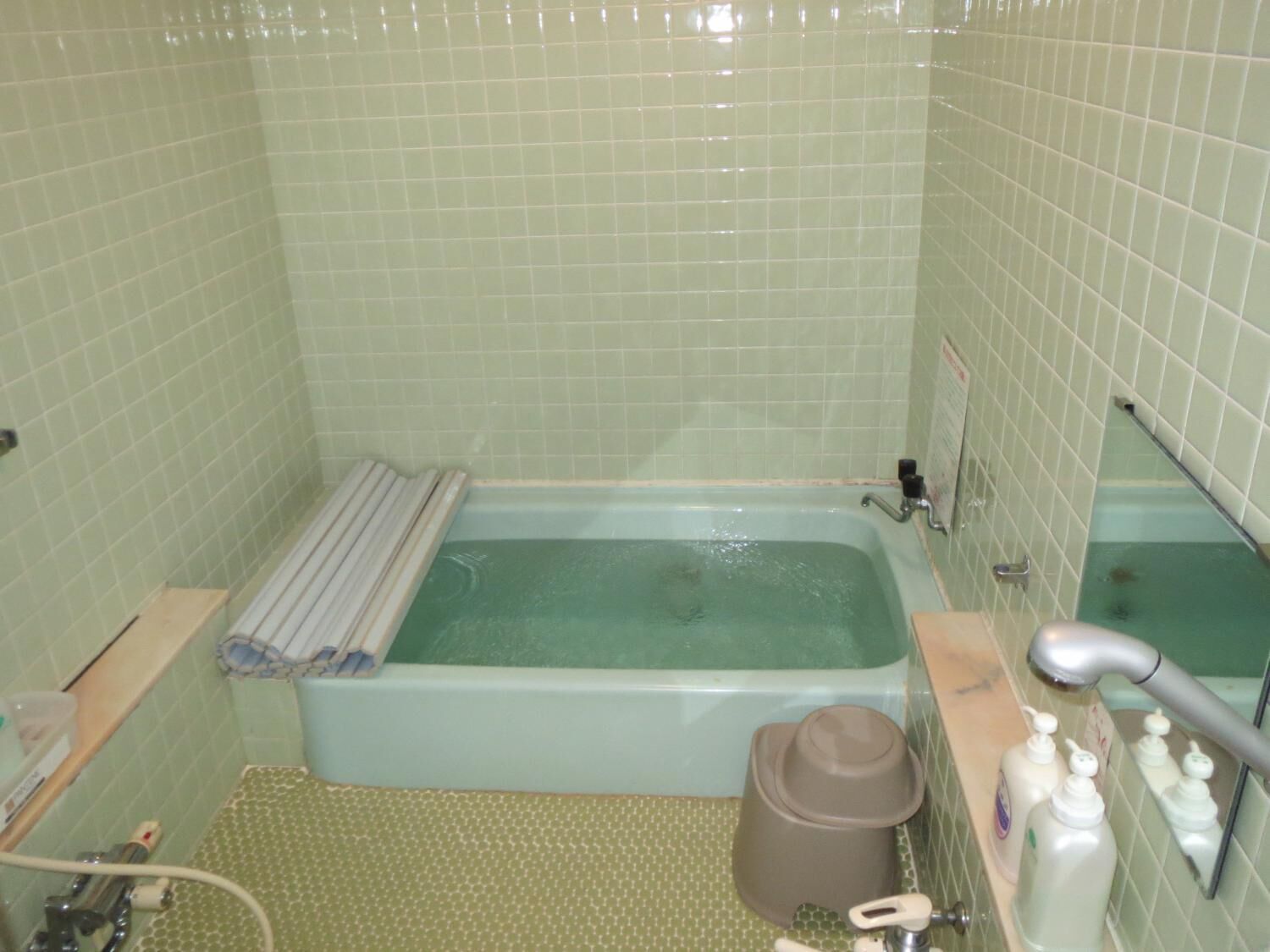 A bathroom with a bathtub, a towel rack, a shower, and toiletries.