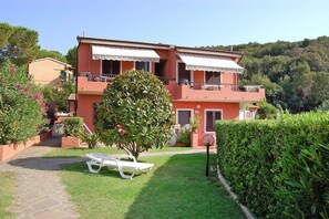 A two-story building with balconies, a garden with a bench, and a pathway leading to the entrance. - Apartment in Capoliveri near Sandy Beaches (Capoliveri)