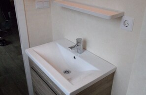 A bathroom with a white sink, a mirror, and a wooden vanity.