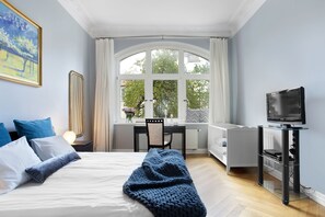 Une chambre d’hôtel avec un lit, un bureau, une télévision et une fenêtre avec des rideaux.