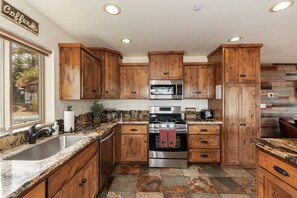 A kitchen with wooden cabinets, stainless steel appliances, and a granite countertop. - Goldmine Lakeview by Destination Big Bear : Luxury Lake & Mountain Views with Pool Table & Hot Tub! Walk to Village! (Big Bear Lake)