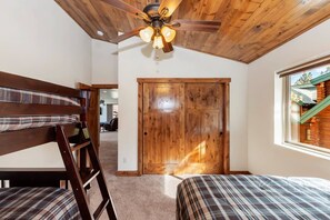 A bedroom with two beds, a wooden ceiling fan, and a large window. - Goldmine Lakeview by Destination Big Bear : Luxury Lake & Mountain Views with Pool Table & Hot Tub! Walk to Village! (Big Bear Lake)