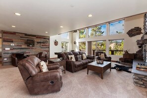 A spacious living area with leather sofas, a coffee table, and a fireplace. - Goldmine Lakeview by Destination Big Bear : Luxury Lake & Mountain Views with Pool Table & Hot Tub! Walk to Village! (Big Bear Lake)