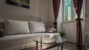A modern living room with a sofa, a glass coffee table, and a window with curtains. - JR Luxury Guesthouse (Split)