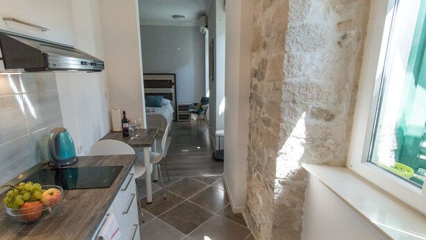 A modern kitchen with a built-in stove, a dining area with a table and chairs, and a view of the outdoors through a window. - JR Luxury Guesthouse (Split)