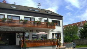 A two-story building with a balcony, a sign reading "Gasthof - Germanyia," and a parked car in front. - Gasthof's Gräbele (Tuebingen)