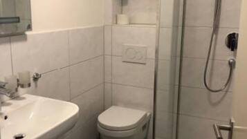 Ein kleines, modernes Badezimmer mit Waschbecken, Toilette und Duschkabine aus Glas.