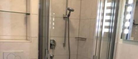 A small bathroom with a glass-enclosed shower, a toilet, and a sink.