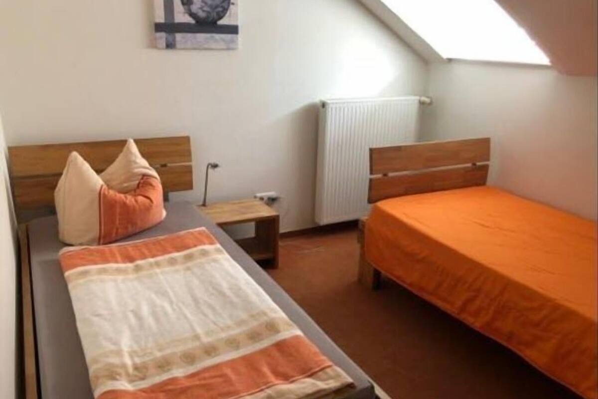 A bedroom with a bed, a nightstand, a radiator, and a skylight.