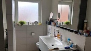 A compact bathroom with a white sink, a mirror, and a window. - Gasthof's Gräbele (Tuebingen)