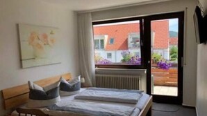 A bedroom with a bed, a chair, a radiator, and a window with a view of buildings and flowers outside. - Gasthof's Gräbele (Tuebingen)