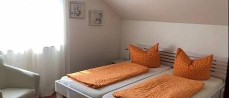 Un apartamento pequeño y de una sola habitación, con cama, una silla y un ventanal.