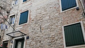 A stone building with a green door, multiple windows with shutters, and a staircase leading to an upper floor. - JR Luxury Guesthouse 2 (Split)