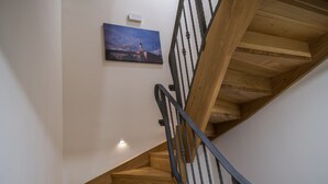 A wooden staircase with a black railing, a painting of a cityscape on the wall, and a light switch on the wall. - JR Luxury Guesthouse 2 (Split)