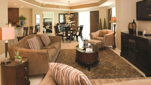 A spacious living room with a sofa, armchairs, a coffee table, and a TV. There is a dining area in the background with a chandelier. - Gorgeous 4bd/3ba Reunion Resort Near Disneyland (Kissimmee)