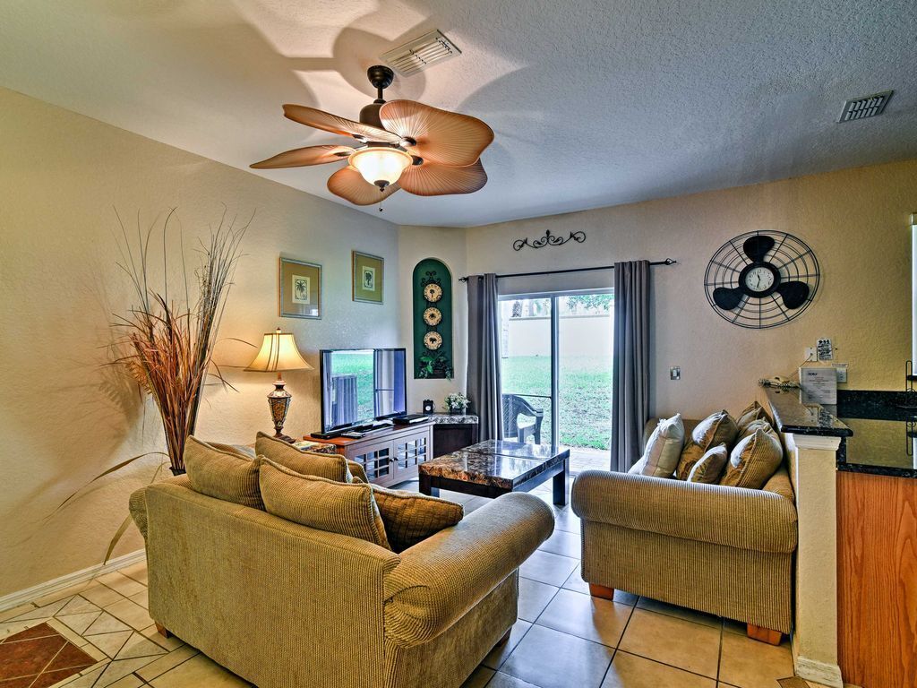 A living room with a ceiling fan, a coffee table, two sofas, a TV, and a view of the outdoors.