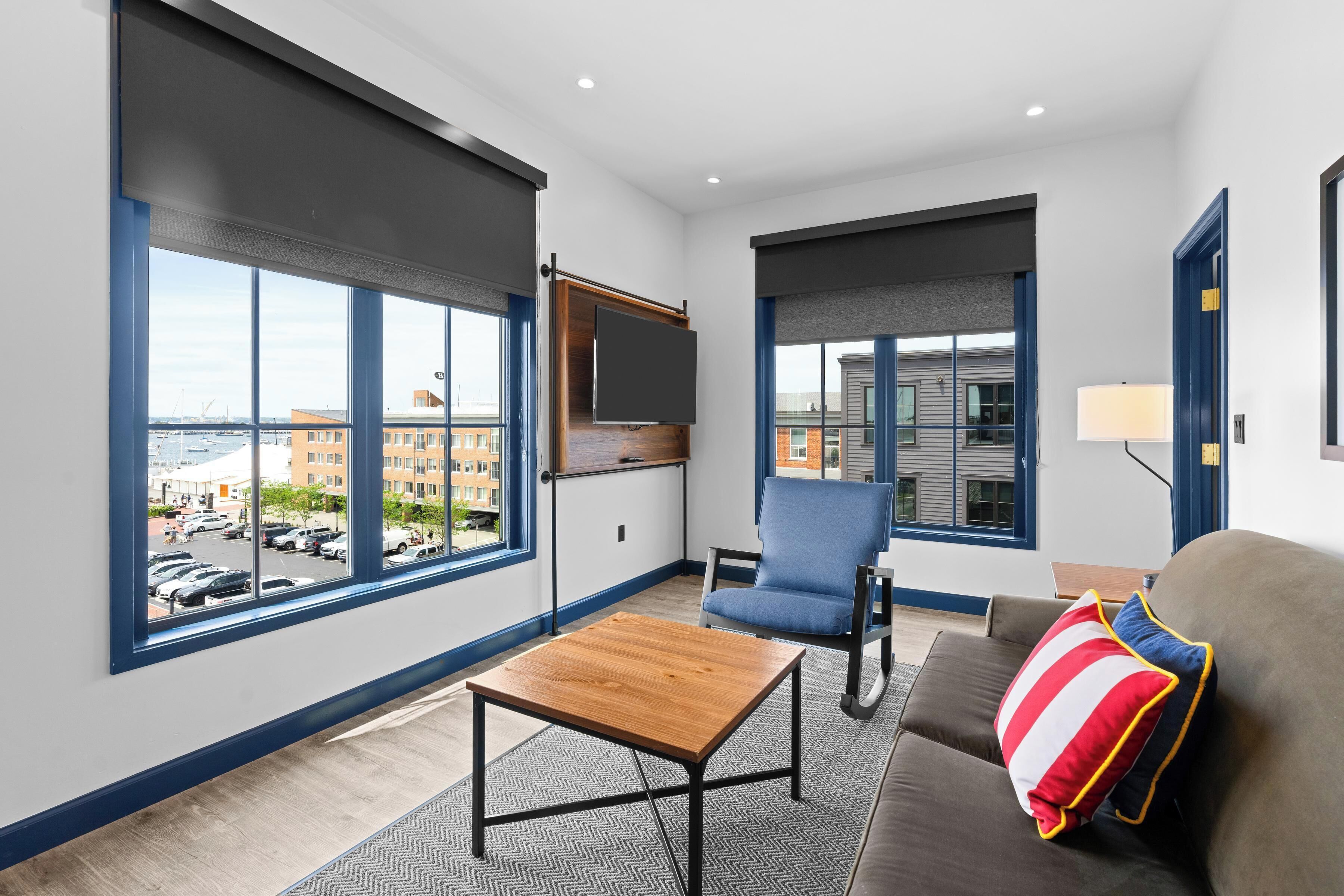 A modern living room with large windows, a flat-screen TV, a sofa, and a coffee table.