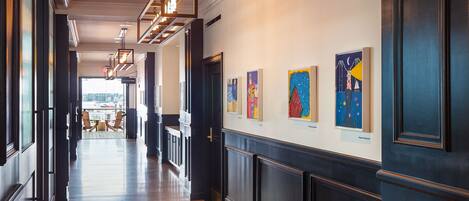 A hallway with wooden floors, dark paneling, and artwork on the walls.