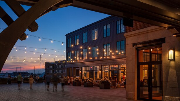 A waterfront building with outdoor seating and string lights.