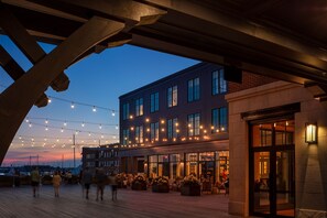 A waterfront building with outdoor seating and string lights. - Hammetts Hotel (Newport)
