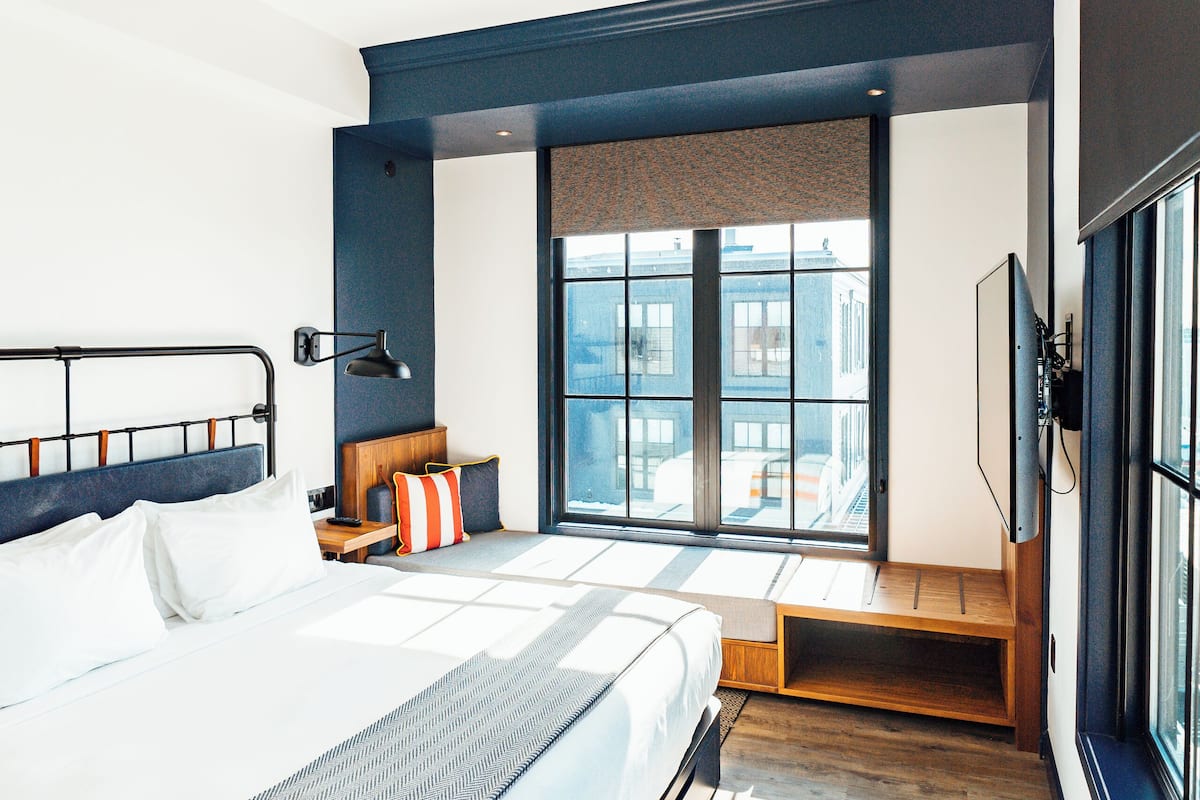 A modern hotel room with a large bed, a seating area with a view, and a television.